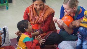 image of two adults and a child. The child is wearing a hearing aid and is communicating in sign language with one of the adults